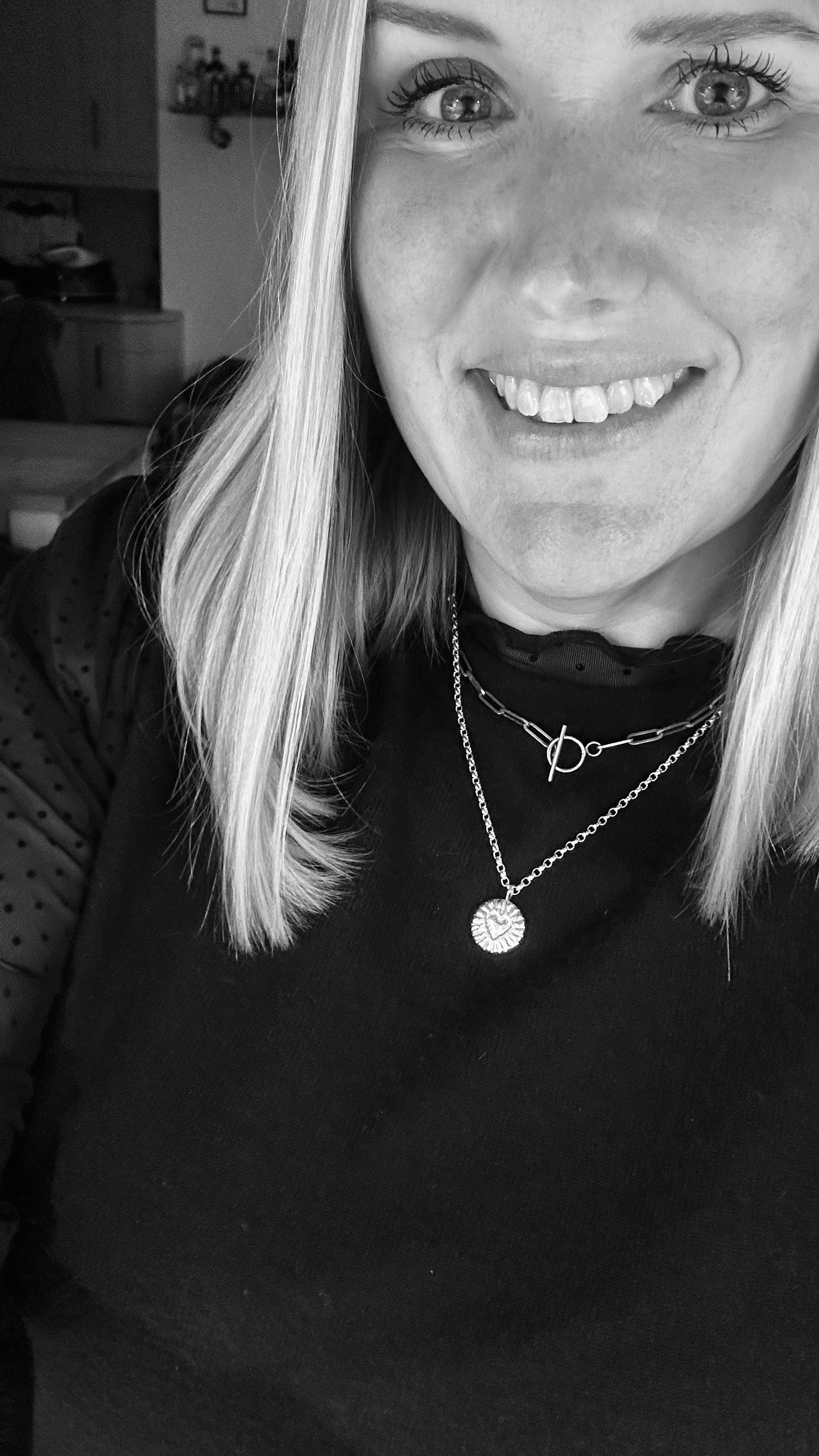 2 necklaces being worn layered together showing a paperclip and heart blast pendant