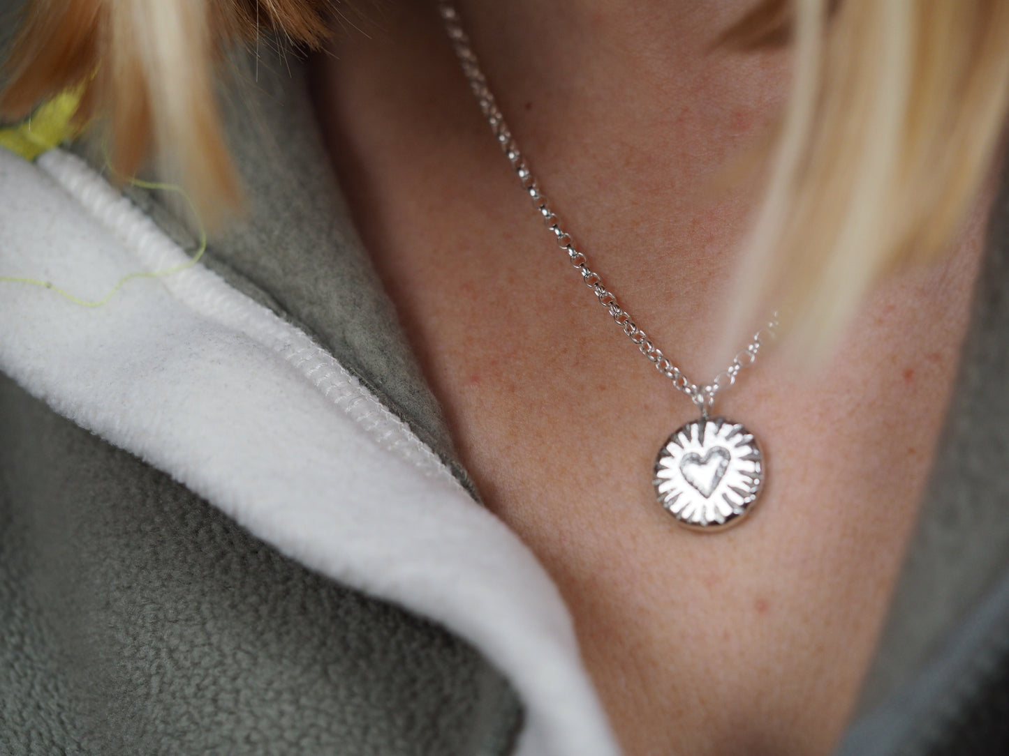 Close-up of a silver necklace with a heart pendant worn by a person.