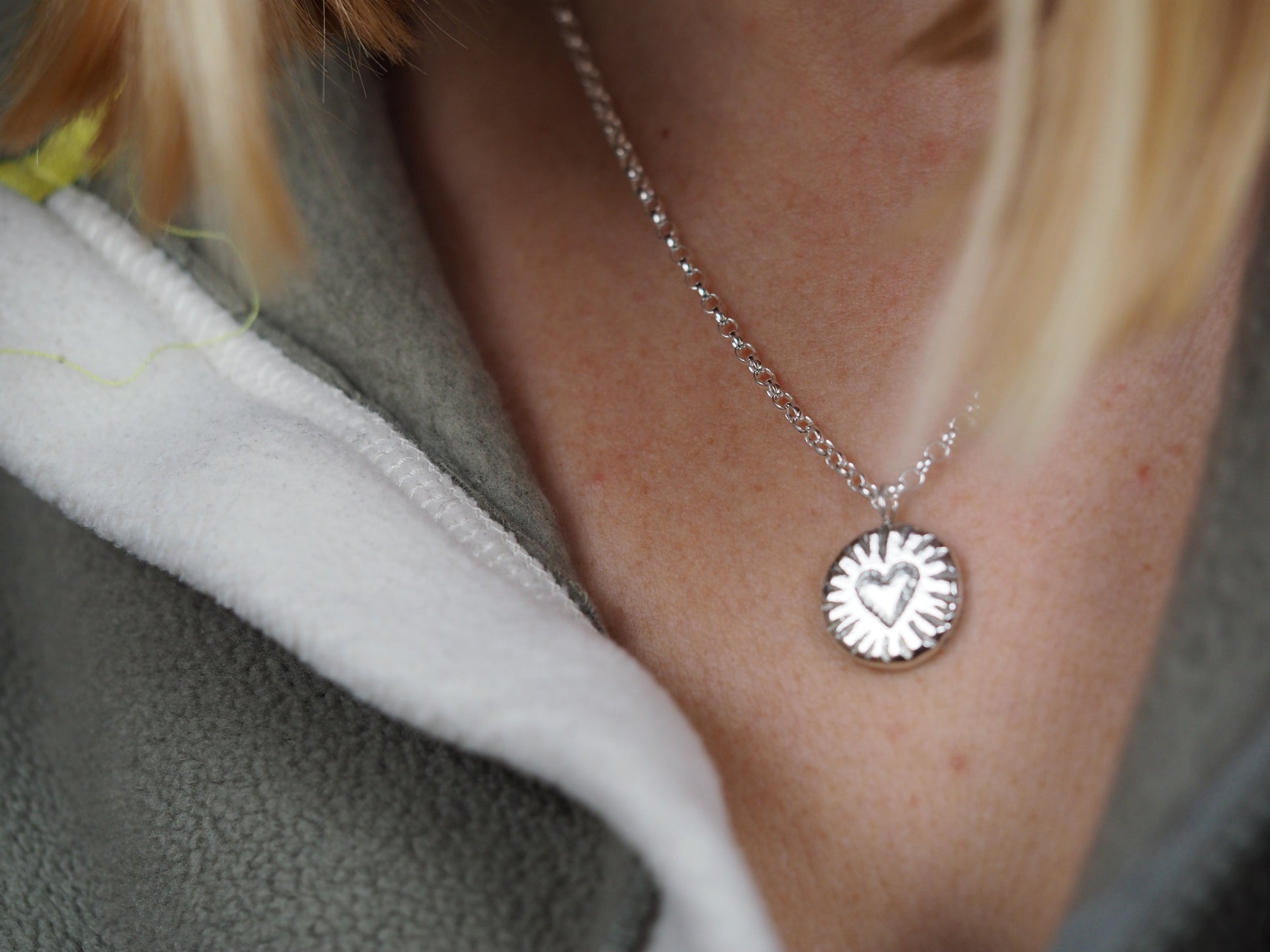 Close-up of a silver necklace with a heart pendant worn by a person.