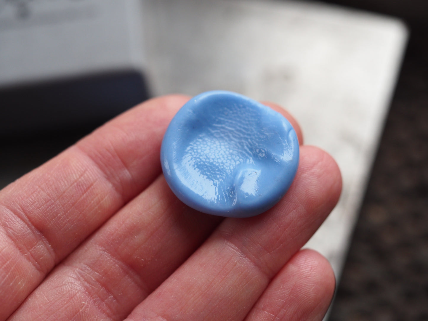 Blue impression mould held in a hand with a blurred background