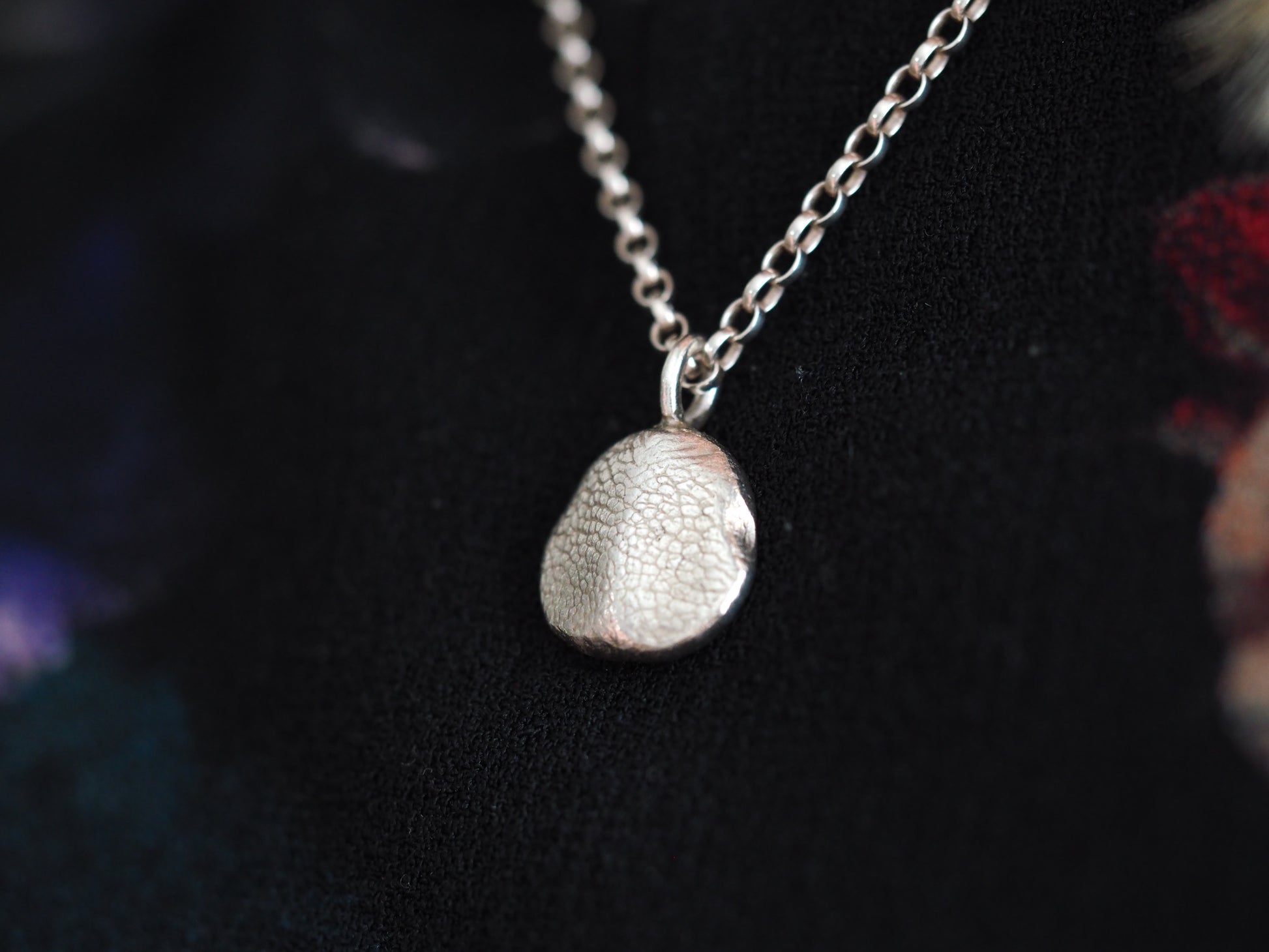 Silver pendant necklace on a dark background
