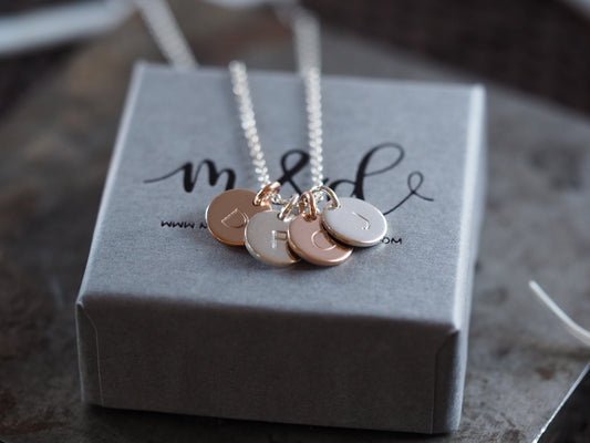 A custom-designed necklace with silver and rose gold mini discs, displayed on a grey box