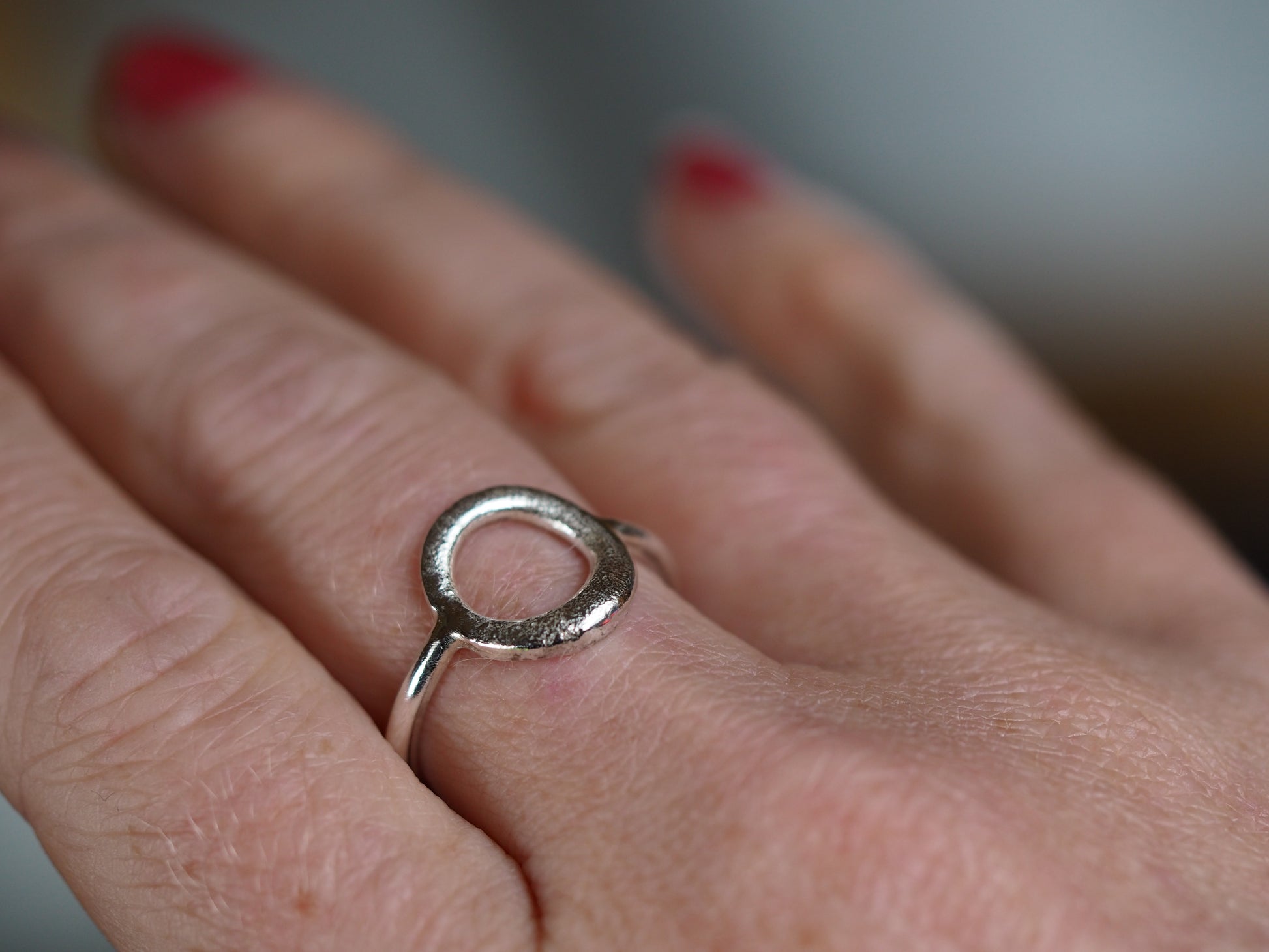 silver circle molten ring being worn on a hand