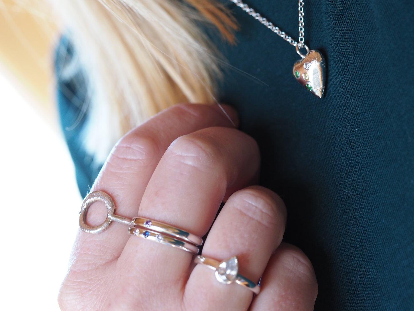image showing a hand with multiple rings and a heart pendant being worn 