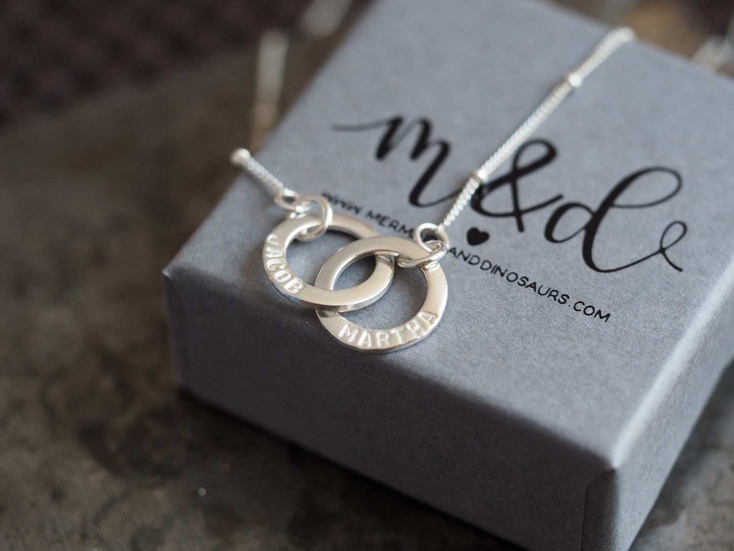 Silver necklace with interlocking rings on a branded box