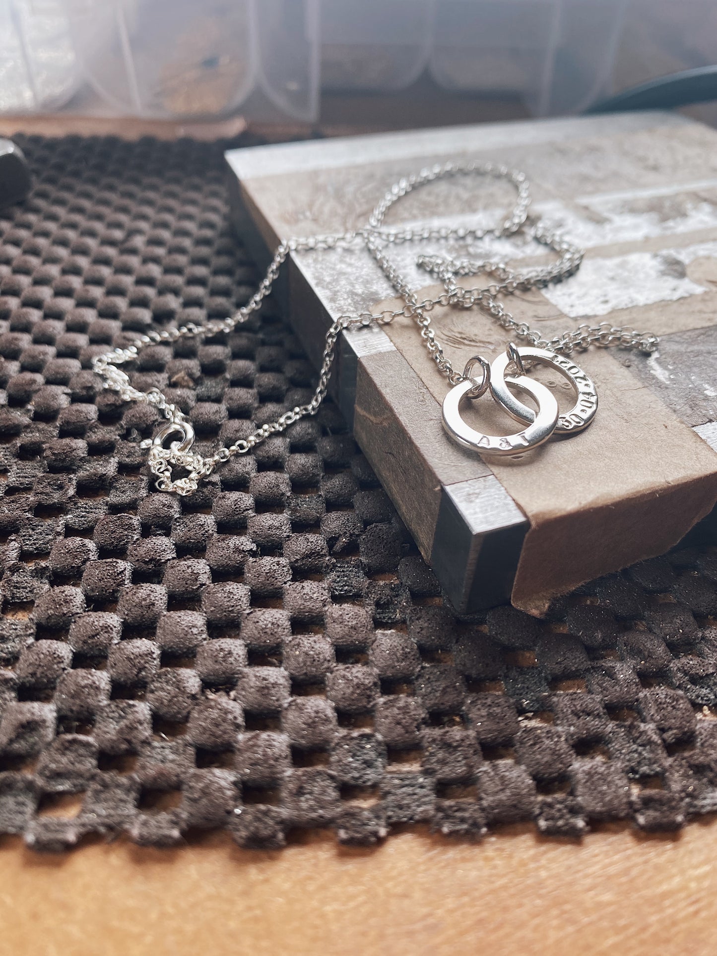 personalised silver washer necklace sat on a steel block