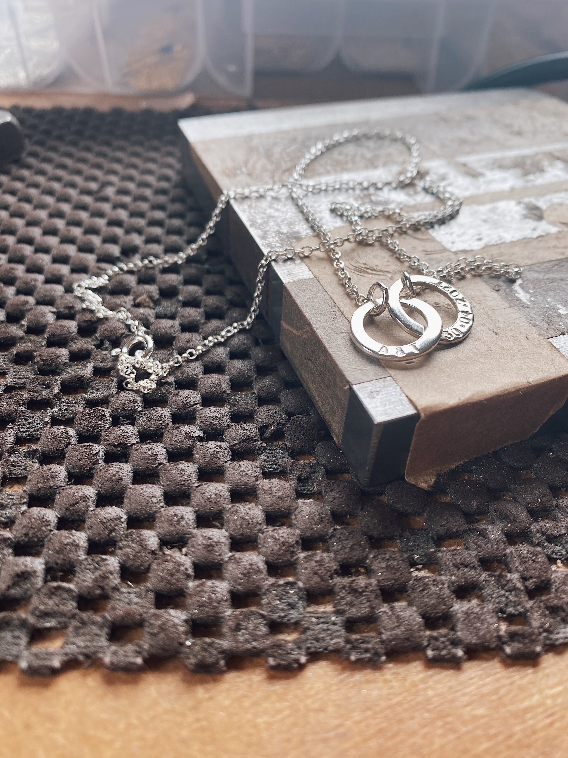 personalised silver washer necklace sat on a steel block