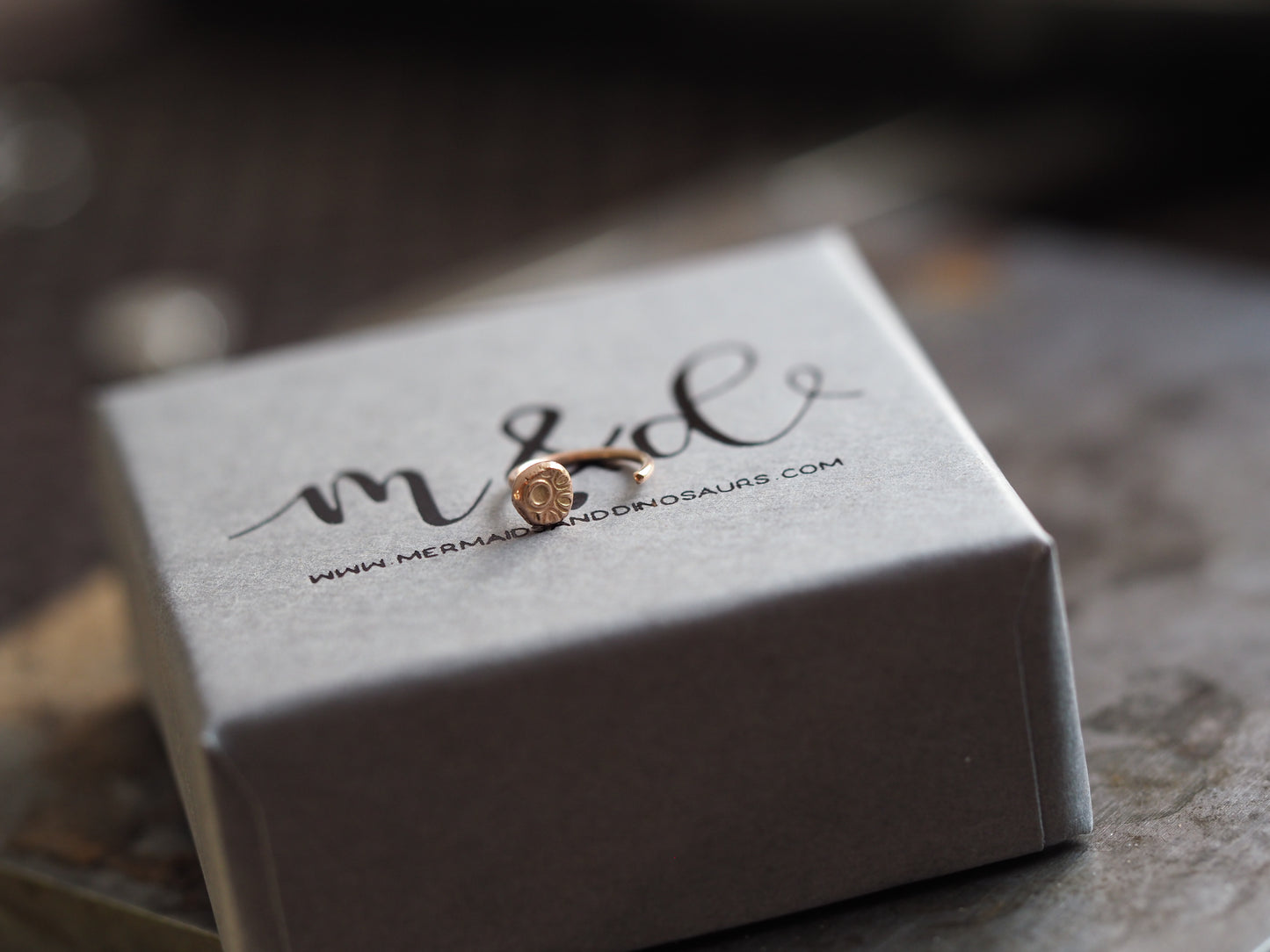 Rose gold helix earring on a branded jewelry box with 'm & d' branding.