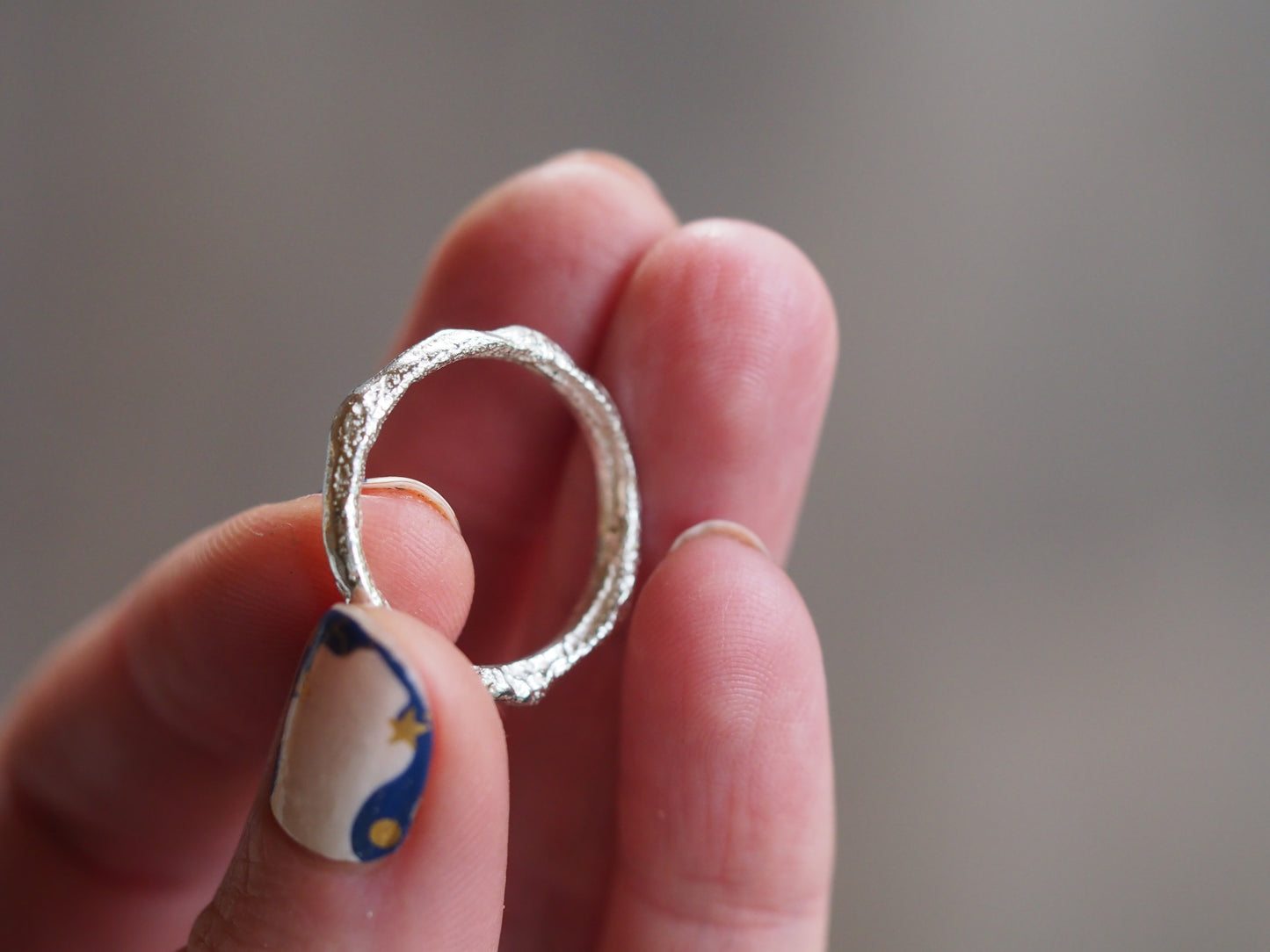 Hand holding a silver ring with a blurred background