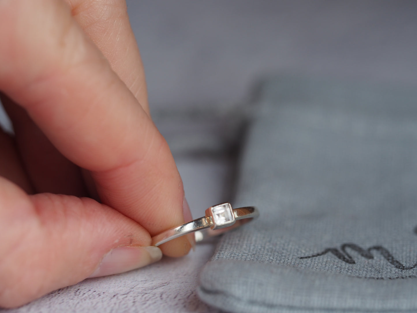 a and holding a silver cubic zirconia ring 