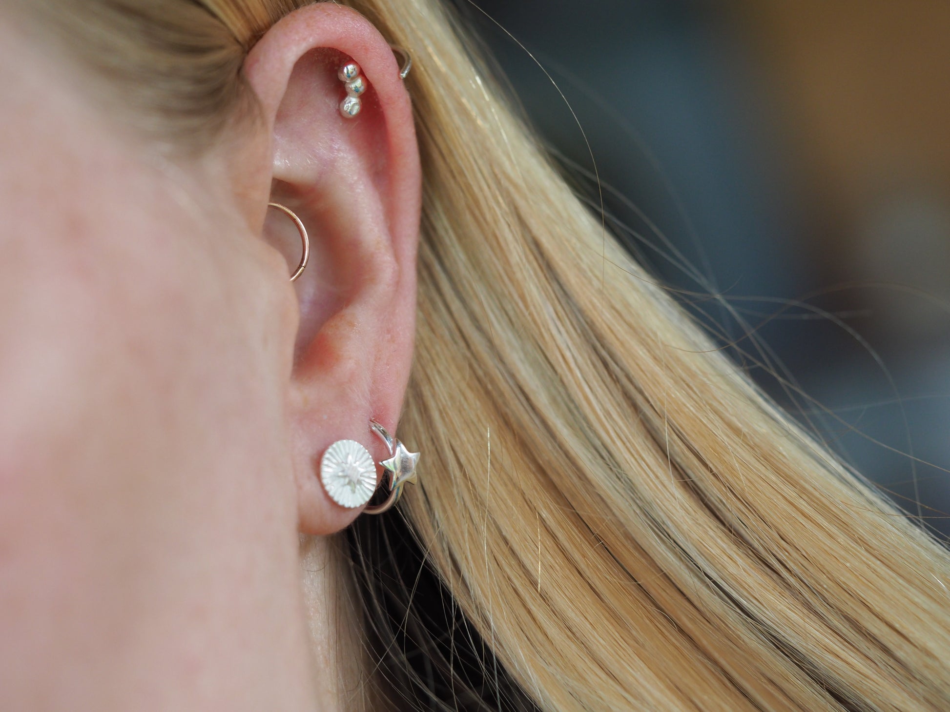 Close-up of an ear with multiple earrings against a blurred background