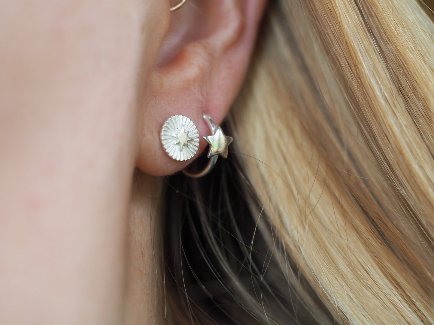 Close-up of a person wearing a silver earring with a textured design.