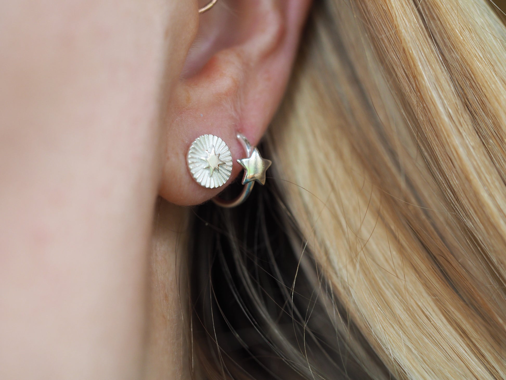 Close-up of a person wearing a silver earring with a textured design.