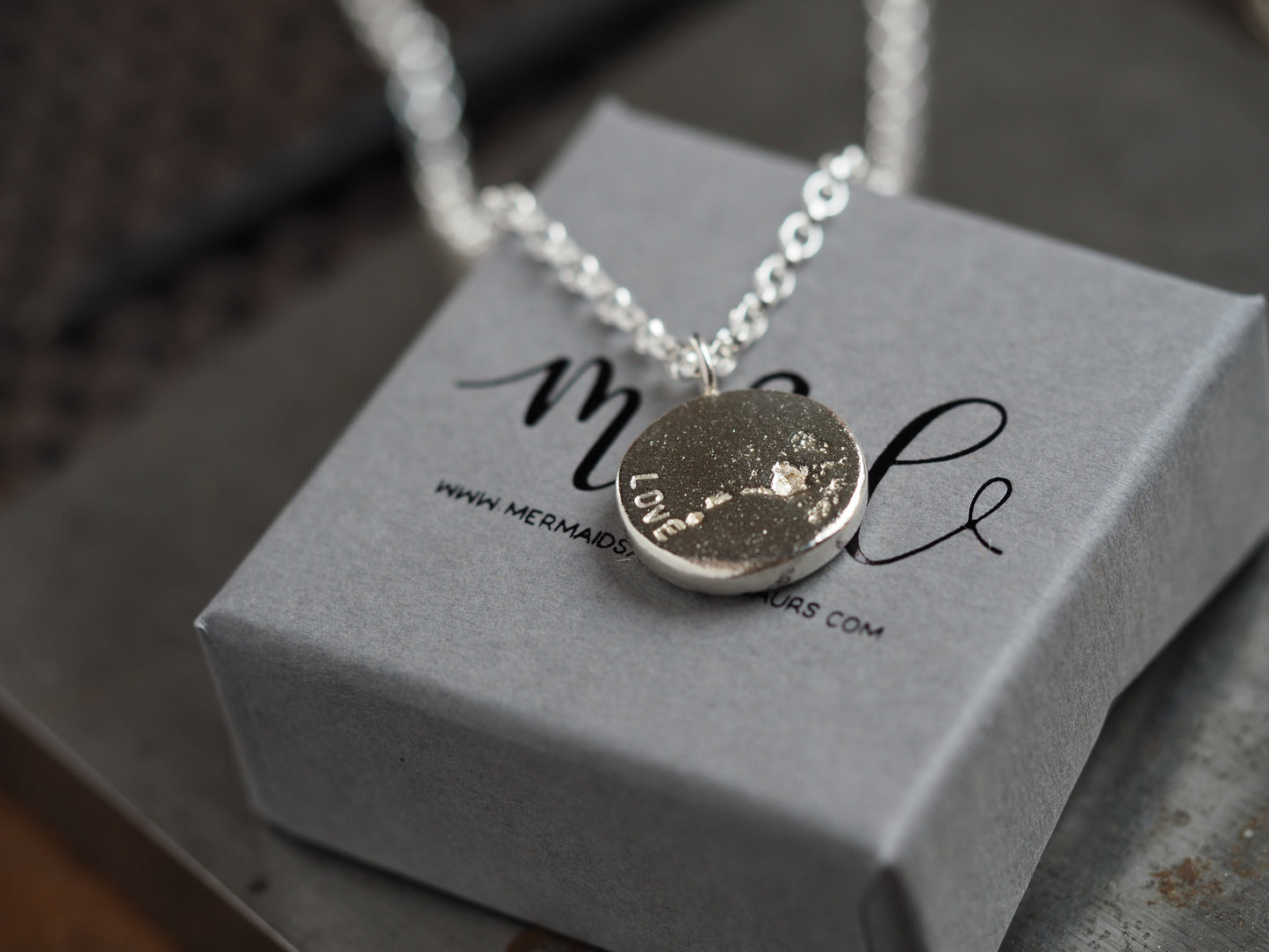 Necklace with a pendant on a grey box with "love" personalised on disc