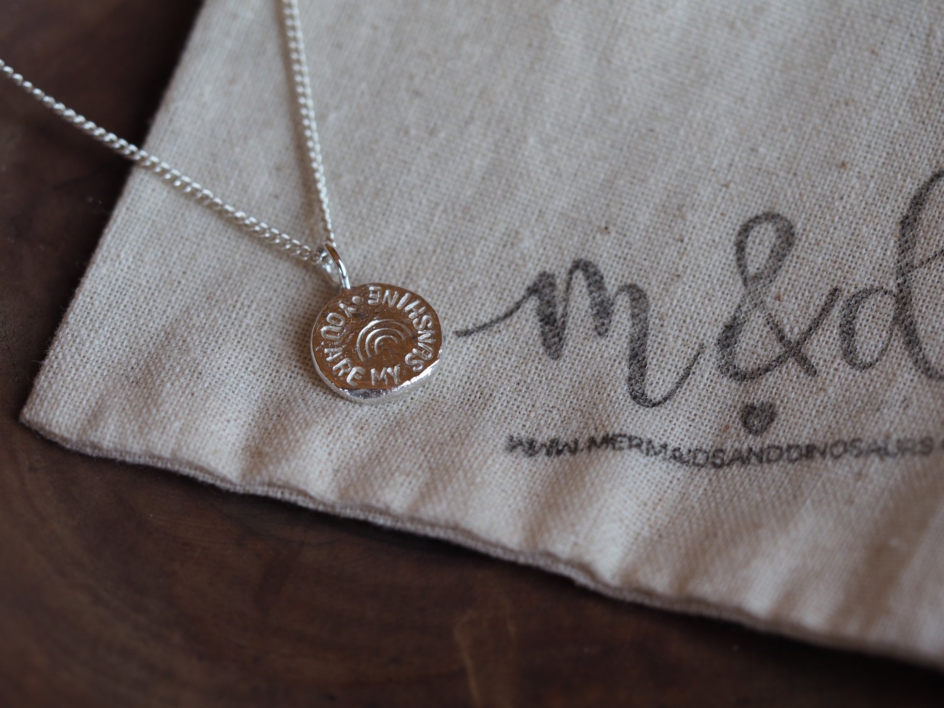'you are my sunshine' necklace on beige m&d branded bag